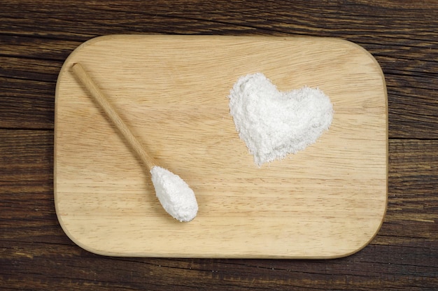 Sea salt in shape of hearts on cutting board, top view