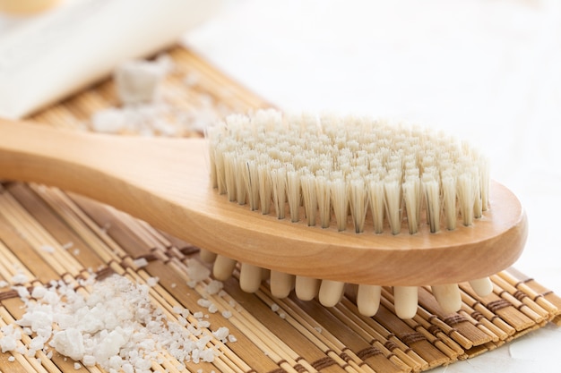 Sea salt , wooden mat, massage wooden brush on white wall