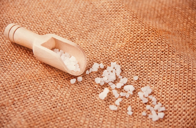 Sea salt in wooden scoop on jute napkin