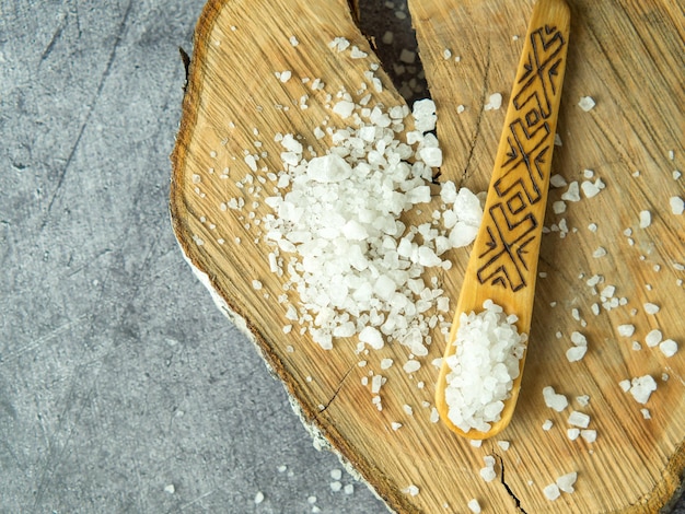 Photo sea salt in a wooden spoon on a wooden background