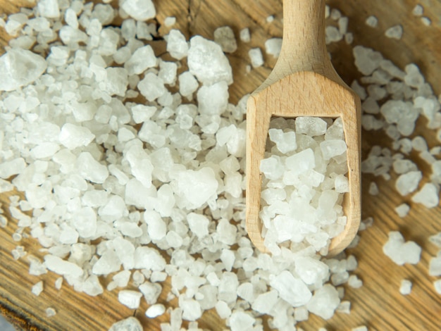 sea salt in a wooden spoon on a wooden background