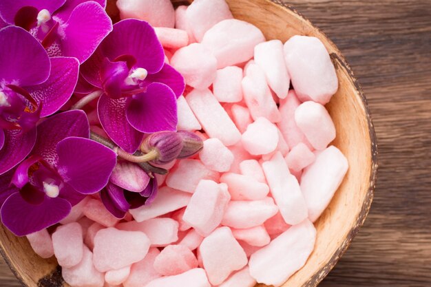 Sea salt on a wooden surface with orchid flower.