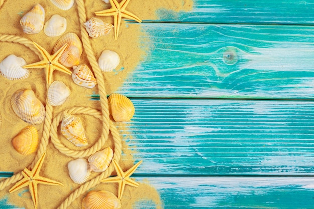 青い木製の背景に海の砂と海の貝殻