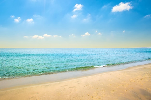 夏の日の青い空に青い水と小さな波の雲と海の砂浜