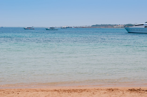 Vista della riva del mare, acqua blu e nave, sfondo estivo.