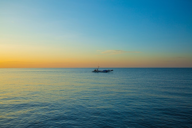 朝の海と小さな漁船、夕暮れの海の真ん中にある小さな漁船