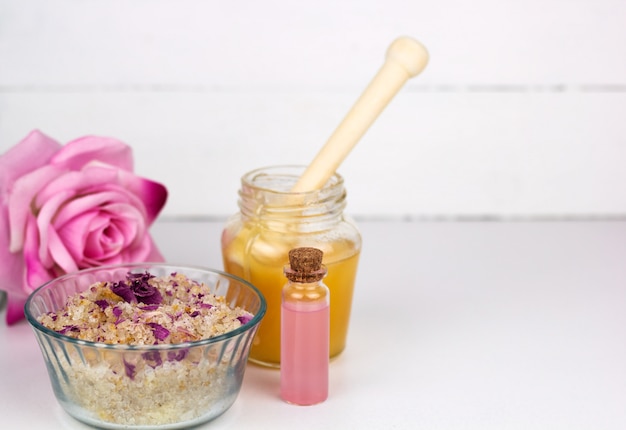 Sea solt scrub, rose essential oil bottle and honey jar copy space