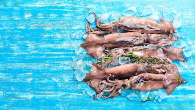 Sea squid on ice on a blue wooden background Seafood On a dark background