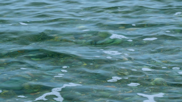 海の石は波の澄んだ水を通して見える 海岸の小石はまだ