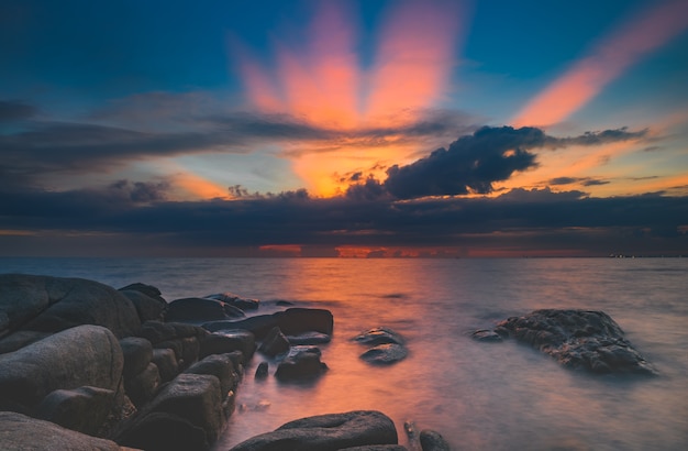 Sea stones and cloud sky in sunset time lighting and dark shadow.