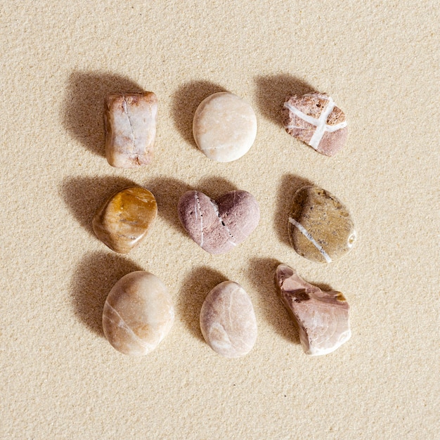 Sea stones neutral colors on natural fine sand background Summer square composition from natural