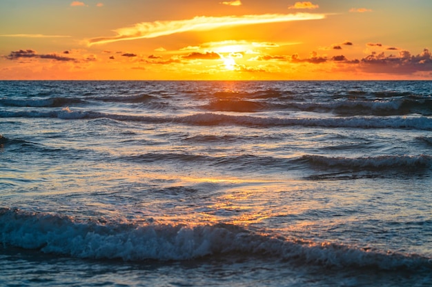 海と空の背景の海景の上に雲の切れ間から空と太陽と海の夕日