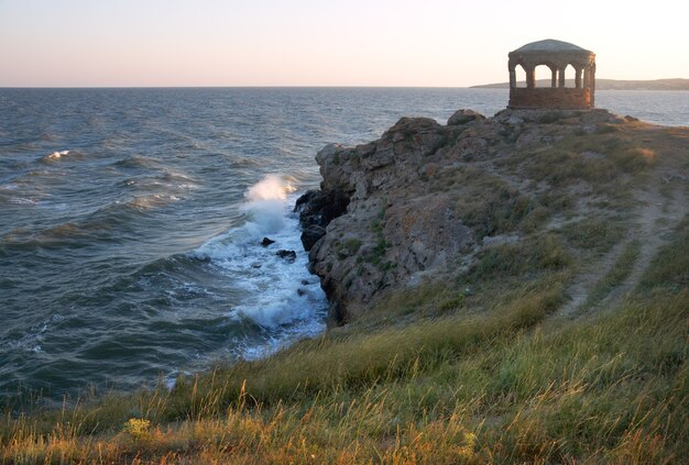 Sea surf great wave break on coastline and cape with pavilion at a distance