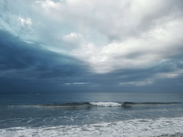 積雲のある暗い空を背景に進行波のある海の景色。