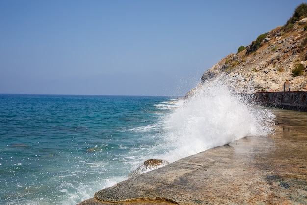 Sea water beats against rocky rocks and makes waves with foam