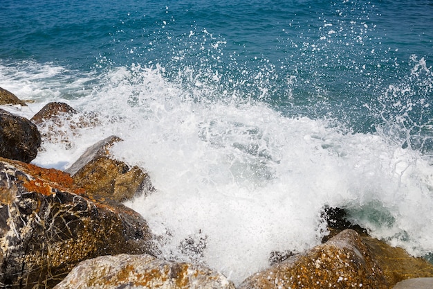 Sea water beats against rocky rocks and makes waves with foam