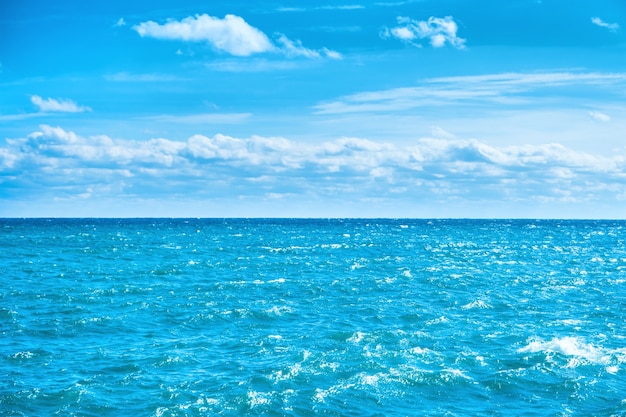 海の水と白い雲と青い空。自然な背景のための海面