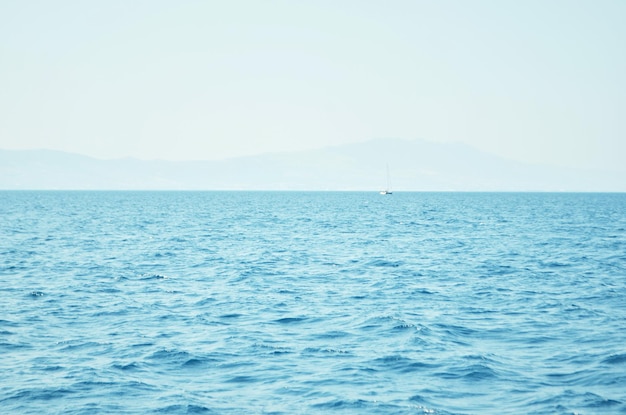 Sea water surface and waves stretch out to the horizon where islands are visible far away.