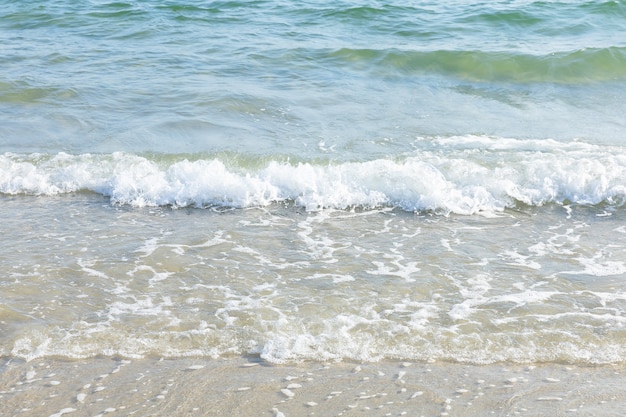 Foto onda di acqua di mare con schiuma sulla spiaggia in giornata di sole