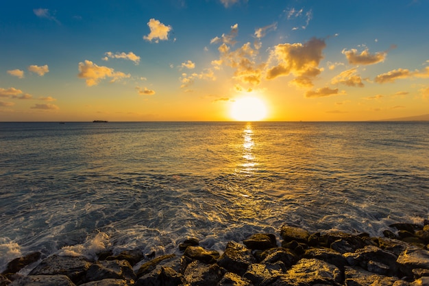 ハワイの日没で海の波が岩を打つ
