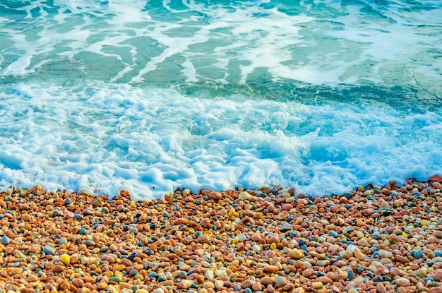 A sea wave runs over a pebble beach.