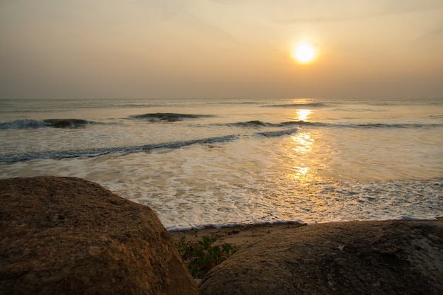 Поверхность морской волны на закате со скалой на фронте