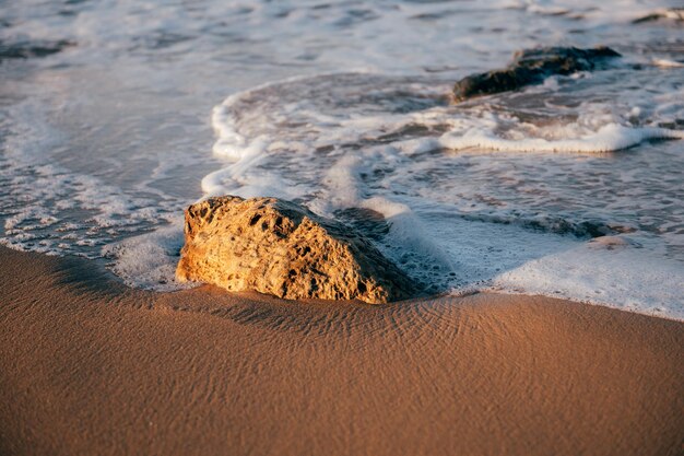 sea waves beach sand and stone at sunset time