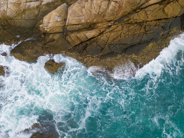 Sea waves breaking against cliff viewed from above