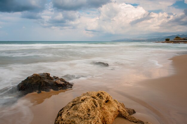 Sea waves crash on the rocks on the shore.