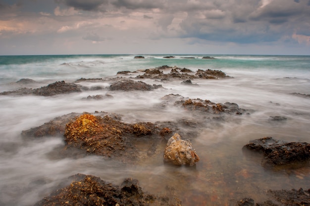 Sea waves crash on the rocks on the shore.