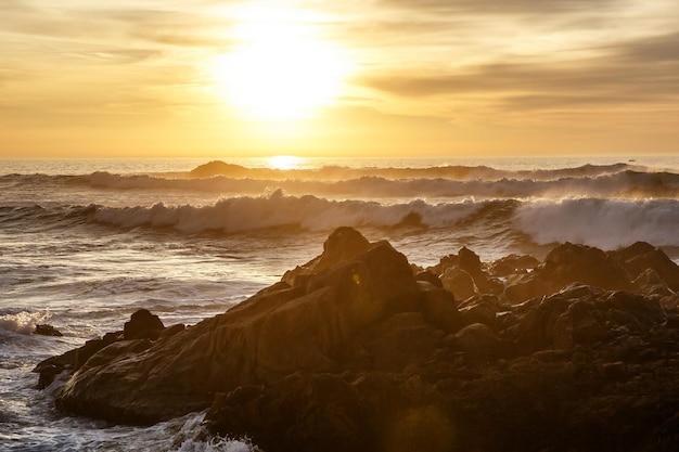 Sea waves crashing onto the rocks on sunset