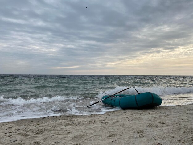 Морские волны разбиваются о заброшенную надувную лодку на берегу моря