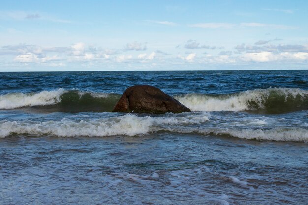 Морские волны и скалы на песчаном берегу. Отдых на море, прилив