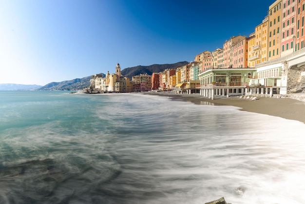 sea waves rushing towards shore by buildings against clear blue sky