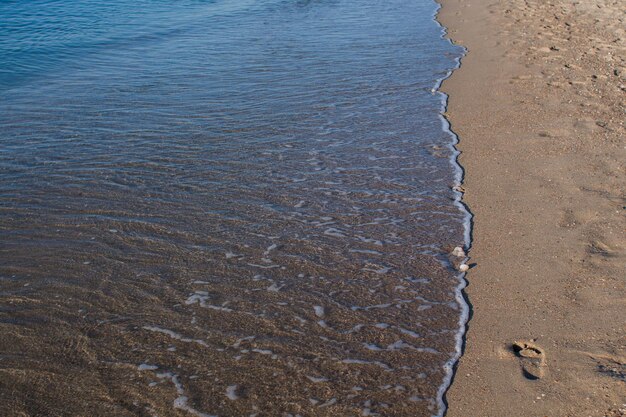 Sea waves on a sandy shore in the afternoon