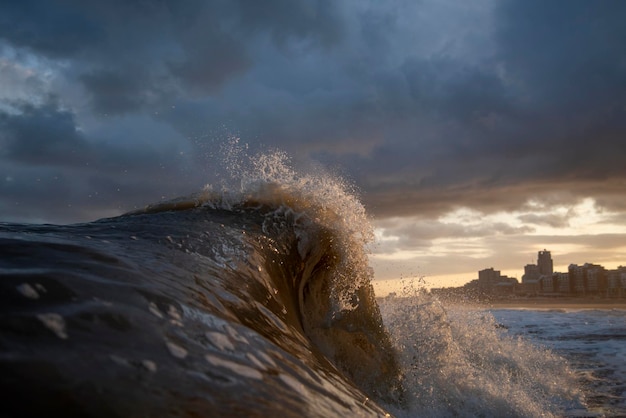 sea waves splashing against cloudy sky during sunset