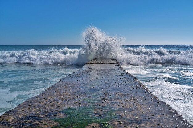 Foto le onde del mare spruzzano sulla riva contro un cielo limpido