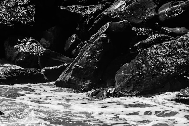 Sea waves with foam and large stones black and white beach photography