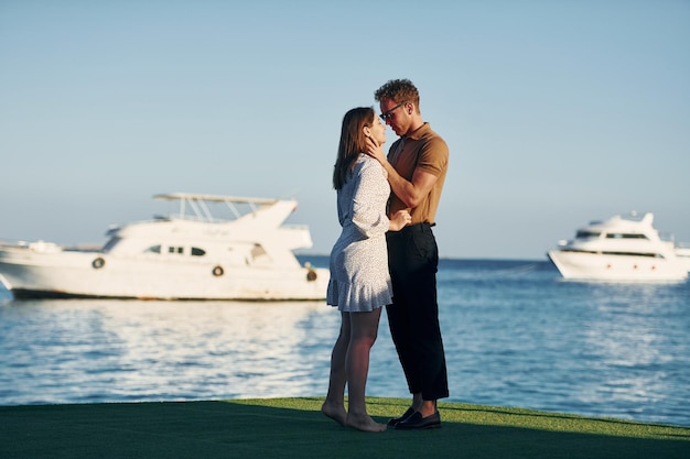 Sea and yacht at background Happy young couple is together on their vacation Outdoors at sunny daytime