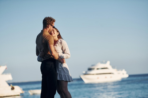 Sea and yacht at background Happy young couple is together on their vacation Outdoors at sunny daytime