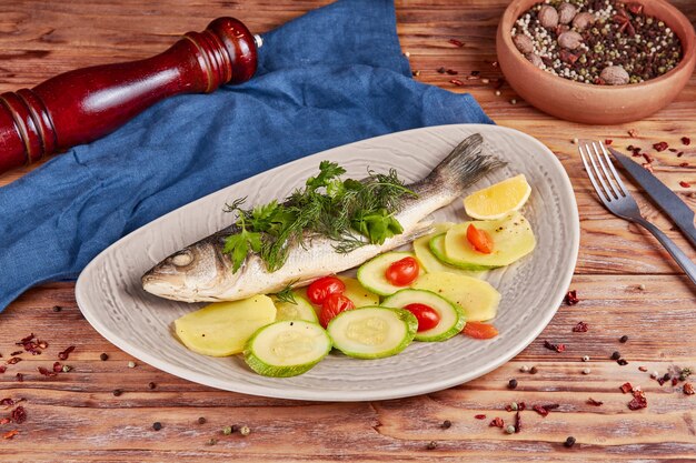 Seabass fish with baked vegetables, wooden