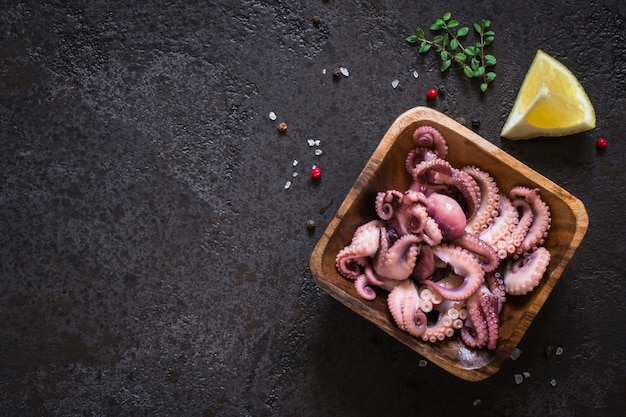 Морепродукты Салат из молодых осьминогов в деревянной миске. Вид сверху с копией пространства