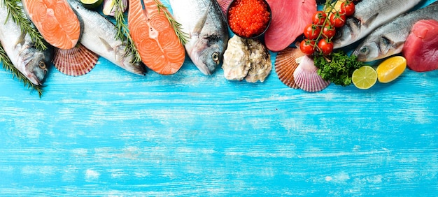 Photo seafood background: salmon, tuna, caviar, oysters, dorado fish and shellfish on a blue wooden background. top view. seafood.