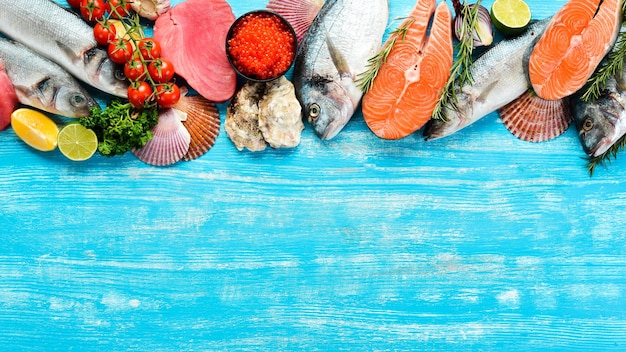 Seafood background salmon tuna caviar oysters dorado fish and shellfish on a blue wooden background Top view Seafood