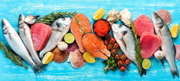 Seafood background salmon tuna caviar oysters dorado fish and shellfish on a blue wooden background Top view Seafood