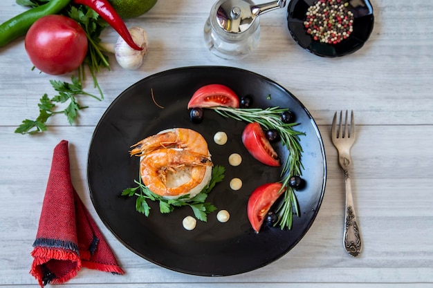 Seafood on a black plate with vegetables