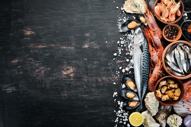 Seafood Fresh fish shrimp oysters and caviar on a black wooden background Top view Free copy space