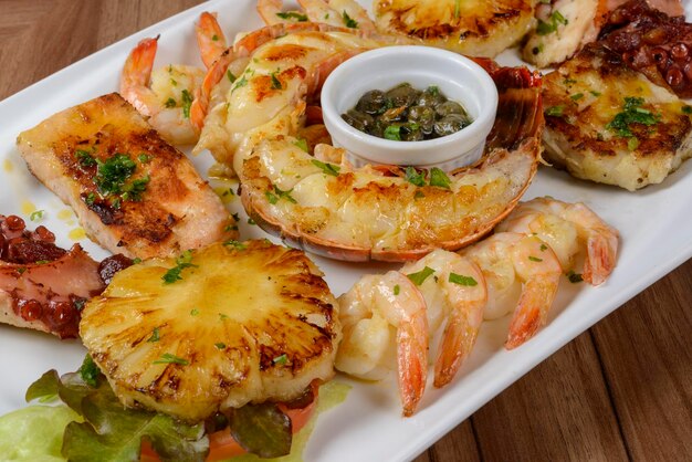 Seafood Lobster shrimp octopus and fish in white bowl on wooden table Brazilian food