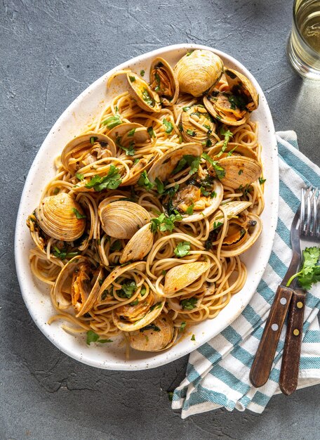 Seafood pasta italian spaghetti alle vongole clams spaghetti on white plate with white wine gray bac