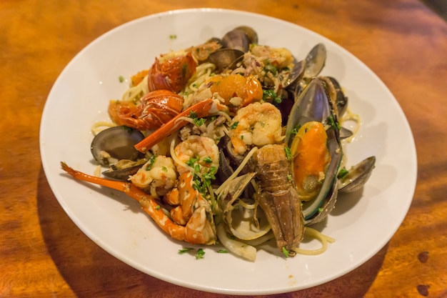 Pasta ai frutti di mare spaghetti con vongole, gamberi, cocktail di pesce nel set con insalata su un tavolo di legno